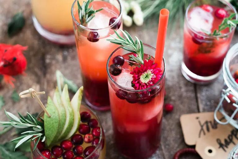 Assorted non-alcoholic drinks in glasses sitting on a table decorated for the Christmas holiday