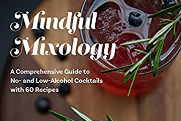 A non-alcoholic beverage in a glass with herbs and olives sitting on a table.